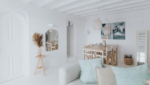 A white interior with a sofa, a dining table, and a mirror. - myMykonos beachfront Villa (Platis Gialos)