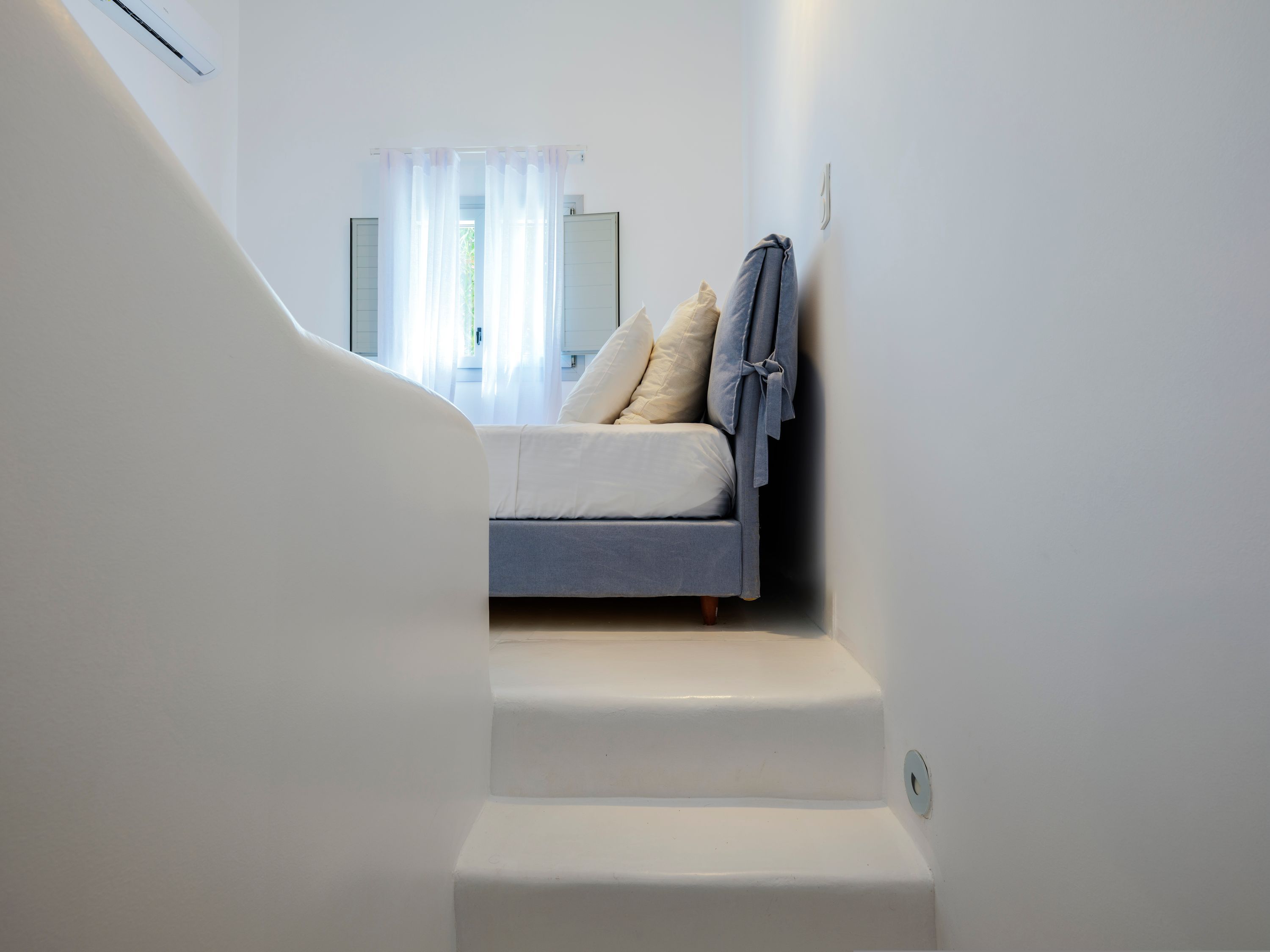 A bedroom with a bed, a nightstand, and a window with curtains.