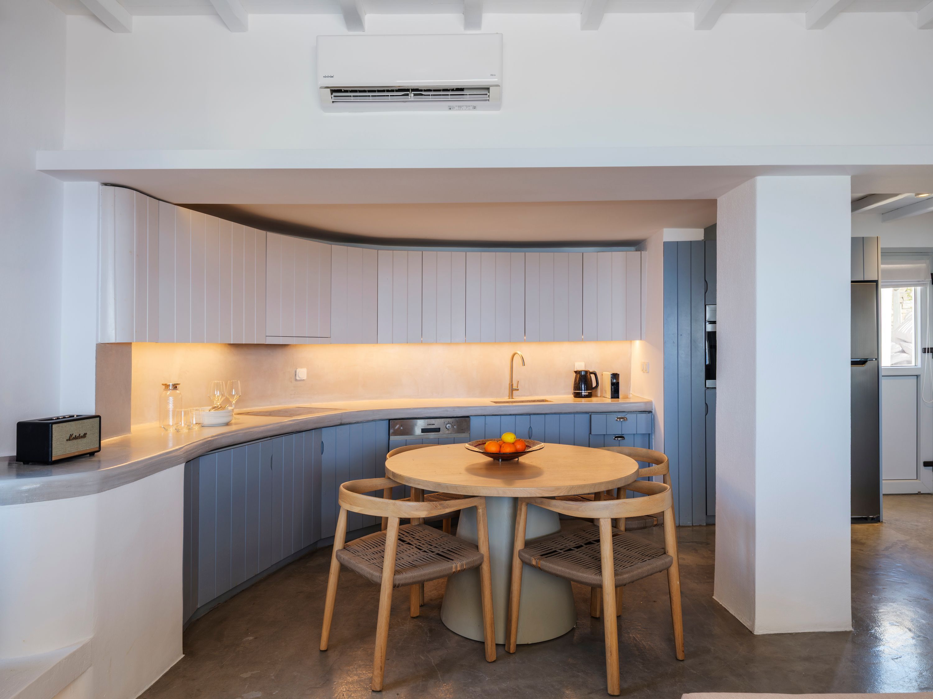 A modern kitchen with a built-in stove, a sink, and a dining area with a round table and four chairs.