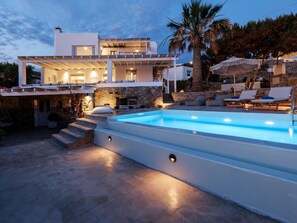 Une villa moderne dotée d’une piscine, d’un espace extérieur aménagé et d’une façade en pierre.