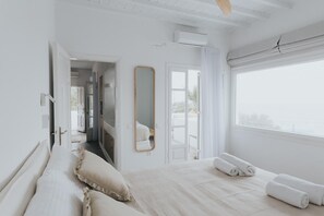 A bedroom with a large bed, a mirror, and a view of the outdoors. - myMykonos II beachfront villa (Platis Gialos)