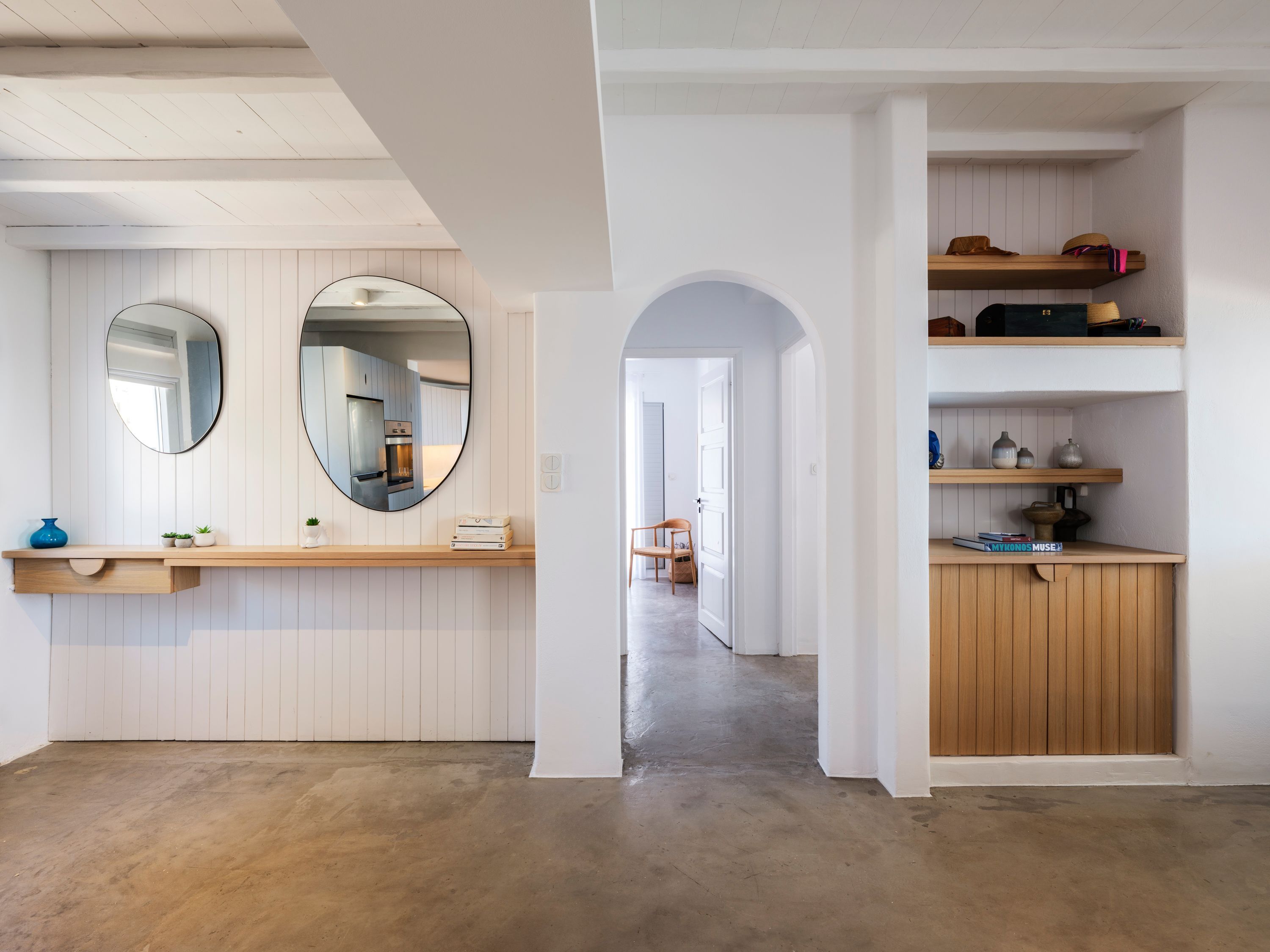 Ein modernes Interieur mit Küchenbereich, Holzregalen und einem Flur zu einem weiteren Zimmer.