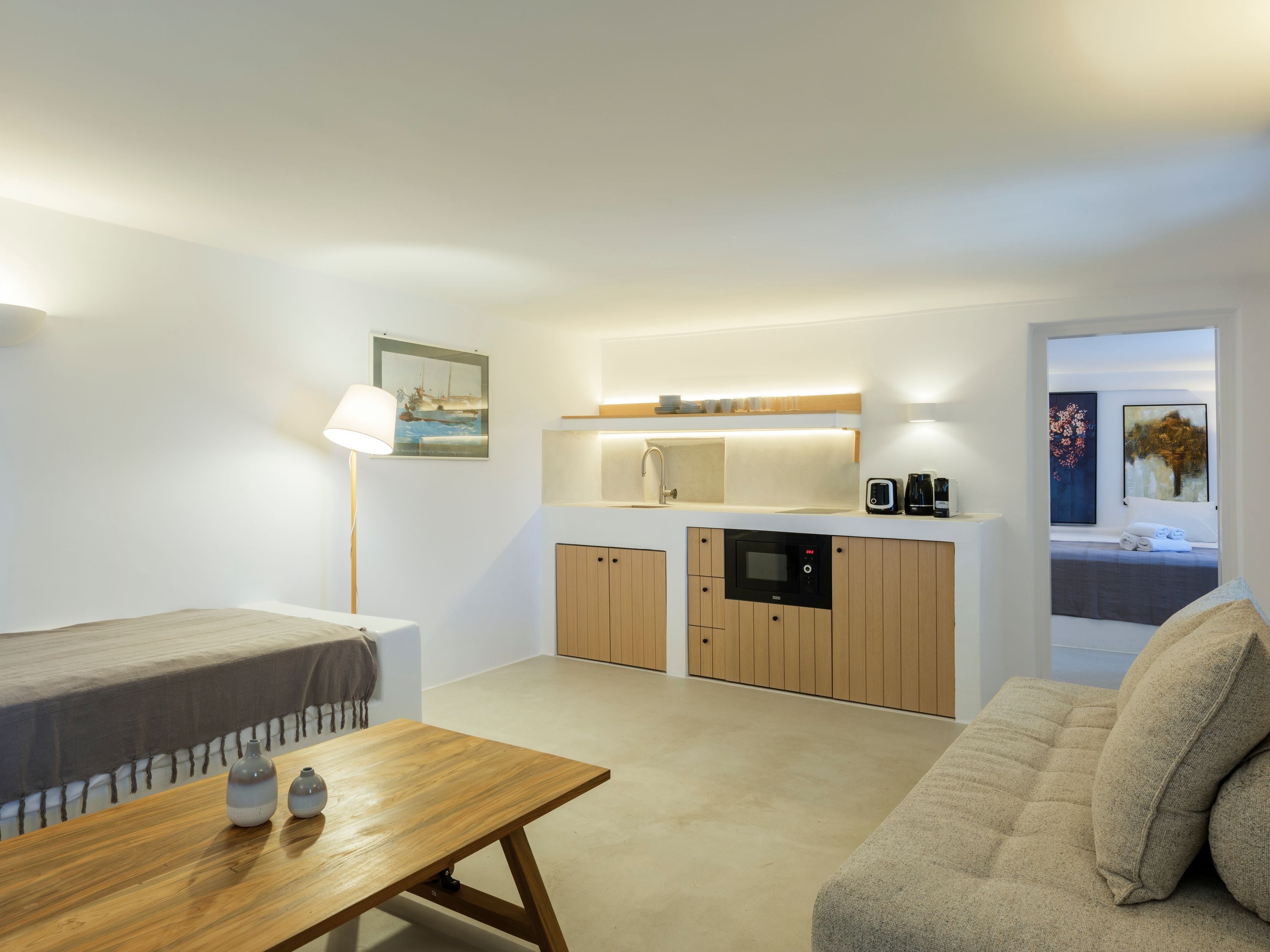 Ein gemütlicher, kompakter Wohnbereich mit Küchenzeile, einer Couch, einem Tisch und einer Lampe.