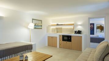 Ein gemütlicher, kompakter Wohnbereich mit Küchenzeile, einer Couch, einem Tisch und einer Lampe.