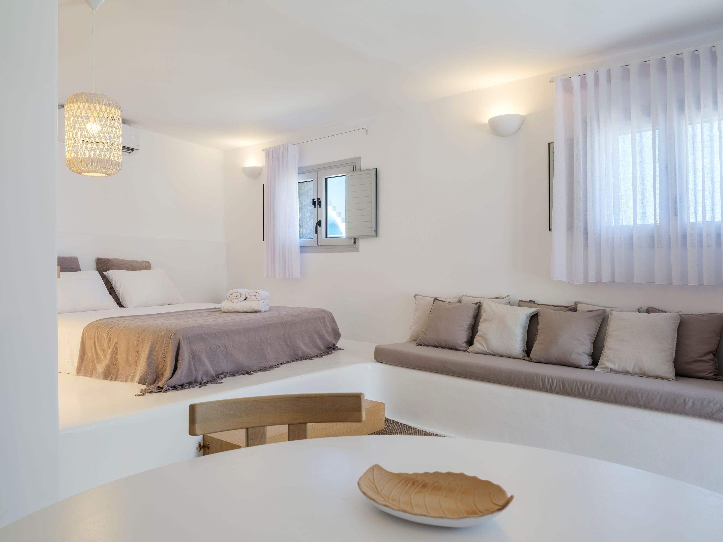 Una camera da letto moderna con un letto, un divano, un tavolo da pranzo e un lampadario.