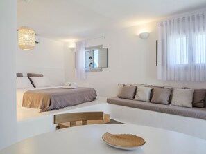 Une chambre à coucher moderne avec un lit, un canapé, une table à manger et un lustre.
