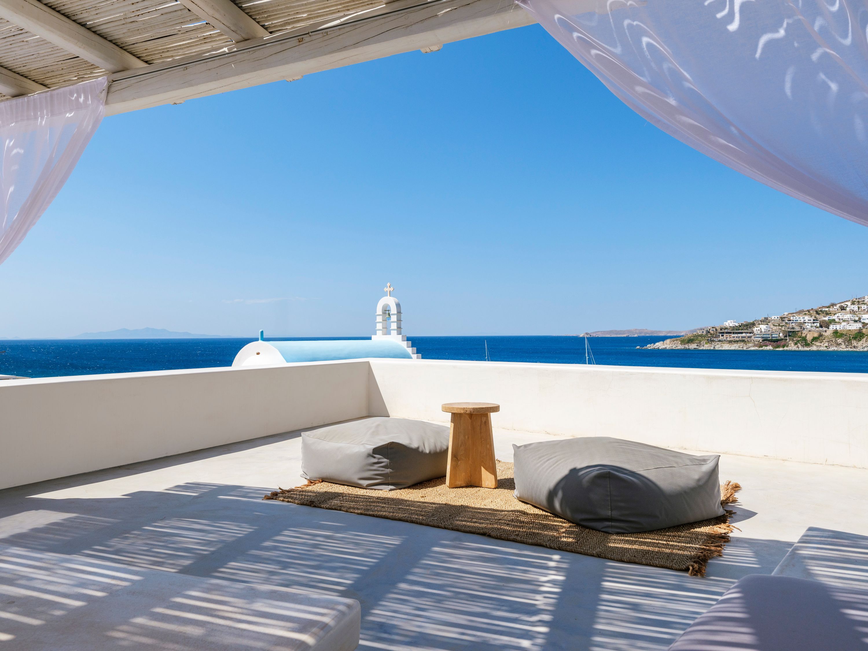 Una terraza con vistas al mar y un edificio blanco con una cruz en la parte superior.