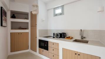 Una cocina moderna con armarios de madera, microondas integrado y cafetera.