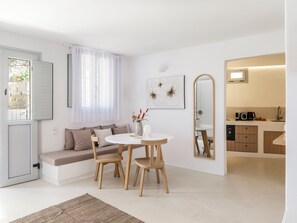 Una sala de estar moderna con un sofá, una mesa redonda de comedor con sillas, una mesa de centro y un espejo grande.