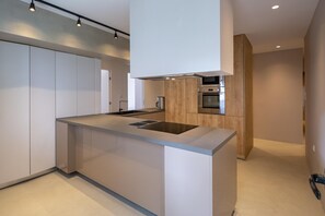 A modern kitchen with a central island, built-in appliances, and a minimalist design. - Hippocrates - Faliro deluxe apartment (Paleo Faliro)
