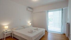 Ein schlicht eingerichtetes Schlafzimmer mit einem Bett, Nachttischen und einem Fenster mit Vorhängen.