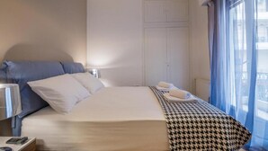 Ett hotellrum med en säng, ett sängbord, en lampa och ett fönster med gardiner.