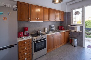 Eine moderne Küche mit Holzschränken, Edelstahlgeräten und einem Fenster mit Blick auf einen Balkon.