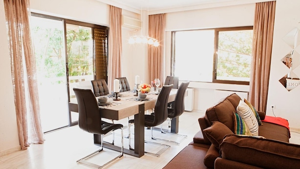 A modern dining area with a wooden table, black chairs, and a brown sofa. - Aries-Glyfada City Center Apartment (Glifada)