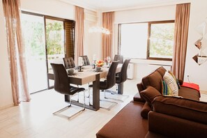 Ein stilvoller Essbereich mit Holztisch, schwarzen Stühlen und einer braunen Couch.