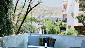 A balcony with wicker furniture, a glass table, and a bowl of fruit. - Aries-Glyfada City Center Apartment (Glifada)