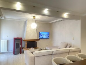 Un saló modern amb una llar de foc, un sofà i una televisió penjada a la paret.