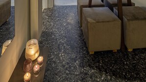 Un salon moderne avec une table à manger ronde, des poufs, un luminaire suspendu et un téléviseur en arrière-plan.