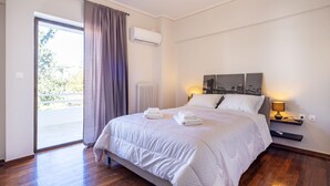 Ein Hotelzimmer mit Bett, Nachttisch, Lampe, einem Fenster mit Vorhängen und Blick ins Freie.