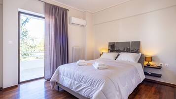 A hotel room with a bed, a nightstand, a lamp, a window with curtains, and a view of the outdoors.