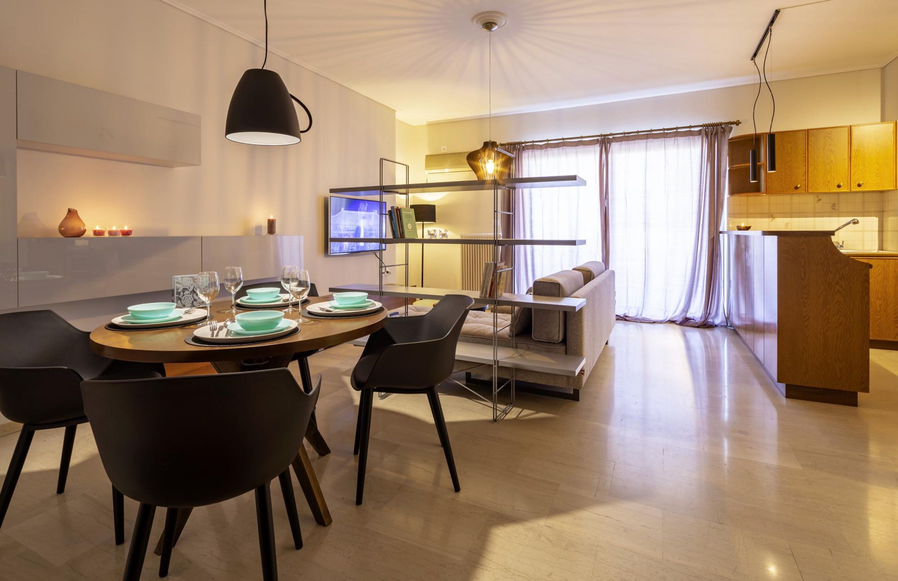 A modern dining area with a round table set for four, black chairs, and a pendant light.