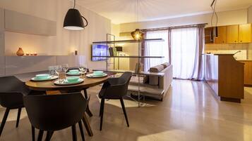 A modern dining area with a round table set for four, black chairs, and a pendant light.