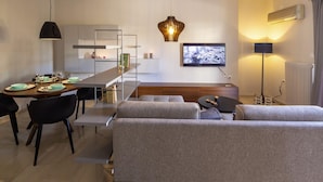 Ein modernes Wohnzimmer mit einer Couch, einem Esstisch und einem Fernseher.