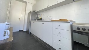 Una cocina moderna con armarios blancos, un refrigerador de acero inoxidable, una cafetera y una estufa.