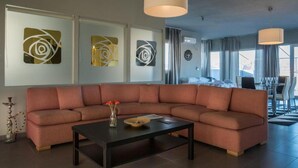 A modern living room with a sectional sofa, a coffee table, and abstract wall art. - Virgo - Loft with Spectacular View to Acropolis (Athina)