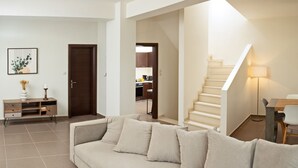 Ett vardagsrum med en beige soffa, ett soffbord i trä och en inramad tavla på väggen.