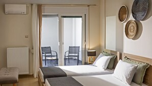 Ett hotellrum med två sängar, ett litet bord, stolar, ett element och utsikt över omgivningen.