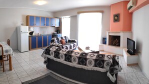 Ein gemütlicher Wohnbereich mit einer Couch, einem Esstisch, einer Küchenzeile und einem Kamin.