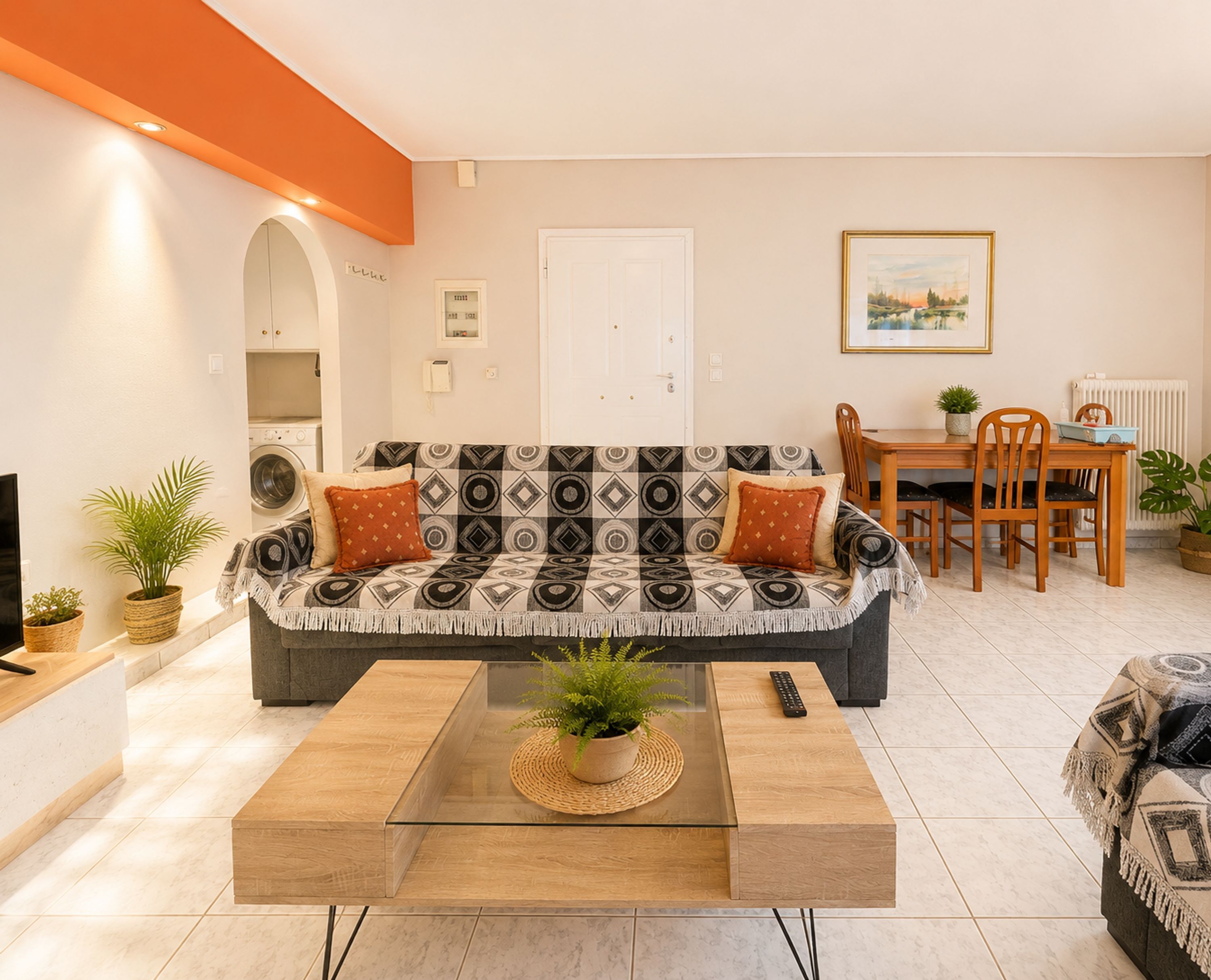 A living room with a sofa, coffee table, dining table, chairs, and a TV.