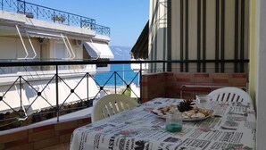 Ein Balkon mit Esstisch, der Blick auf die Küste freigibt.