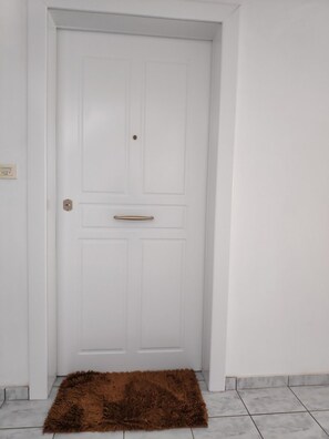 Una puerta blanca con manija y un pequeño orificio para llave.