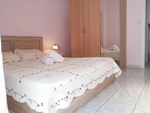 Una cama bien hecha con una colcha blanca y una lámpara en la mesita de noche.