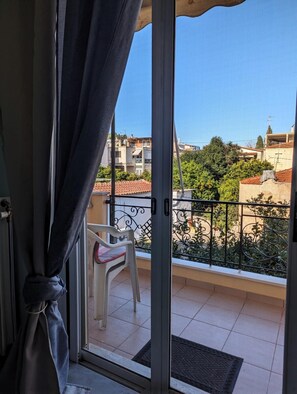 A balcony with a view of a residential area, a white chair, and a metal railing.