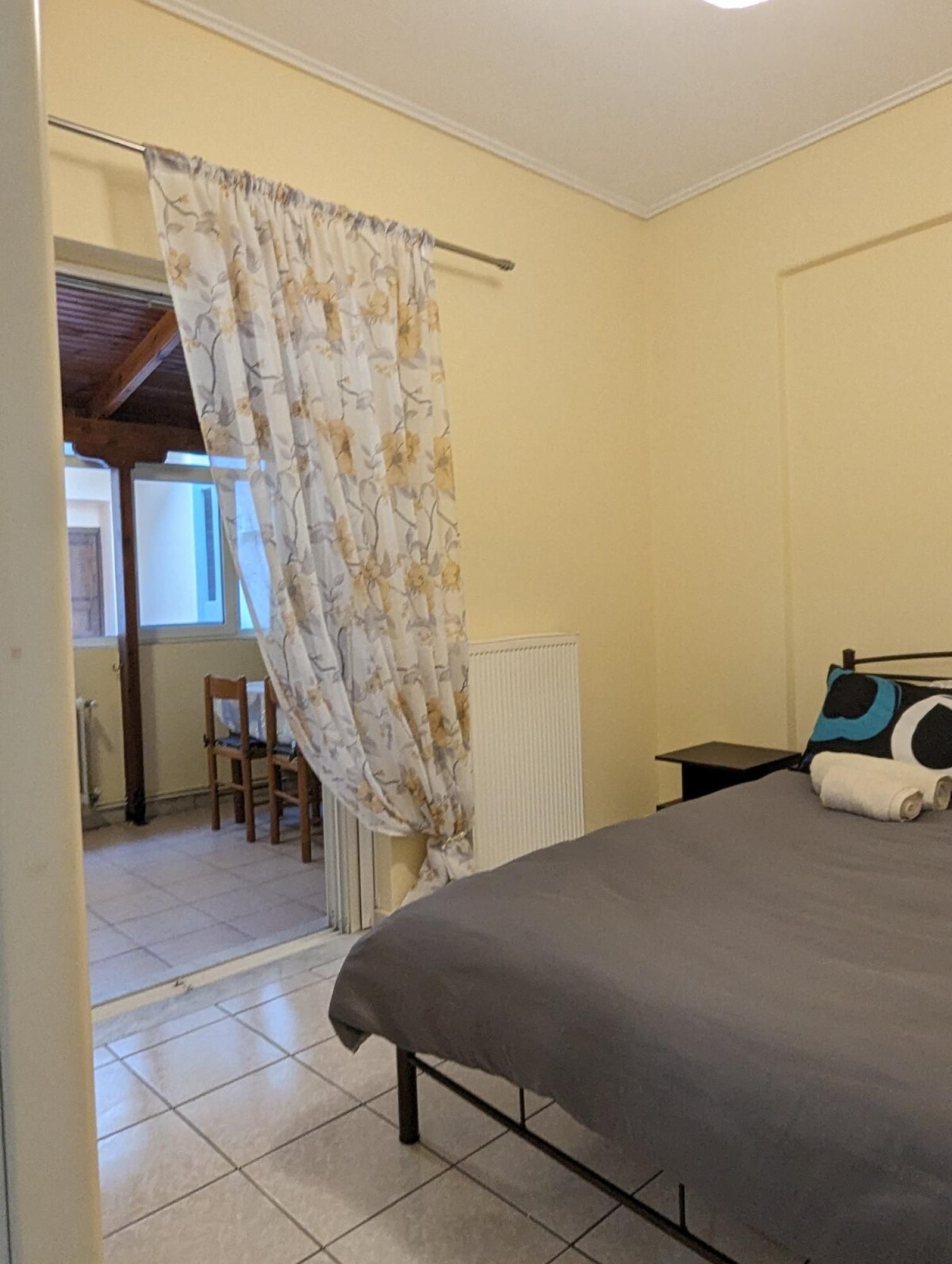 A bedroom with a bed, a chair, a radiator, and a curtain.