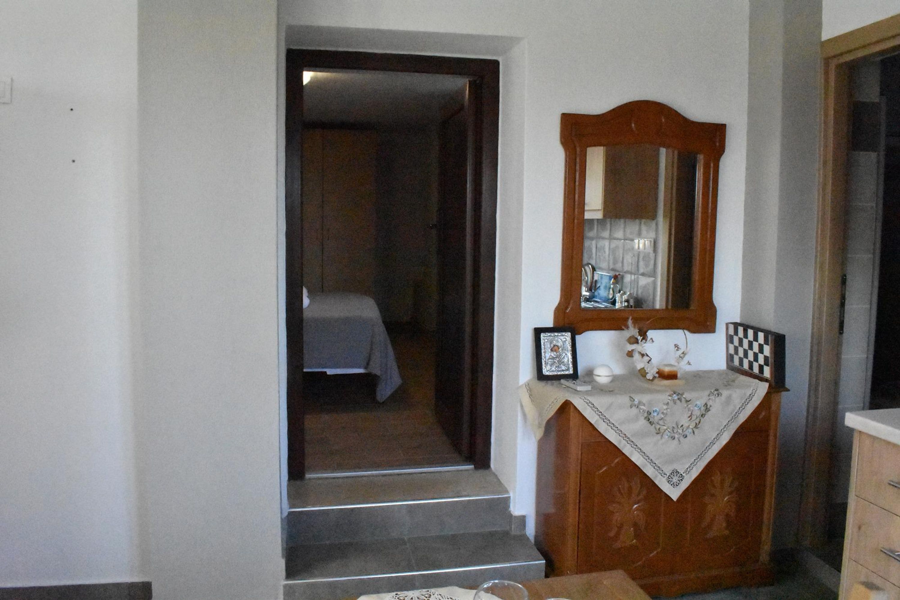 Quarto com penteadeira de madeira, espelho, quadro emoldurado e uma mesinha com tecido.