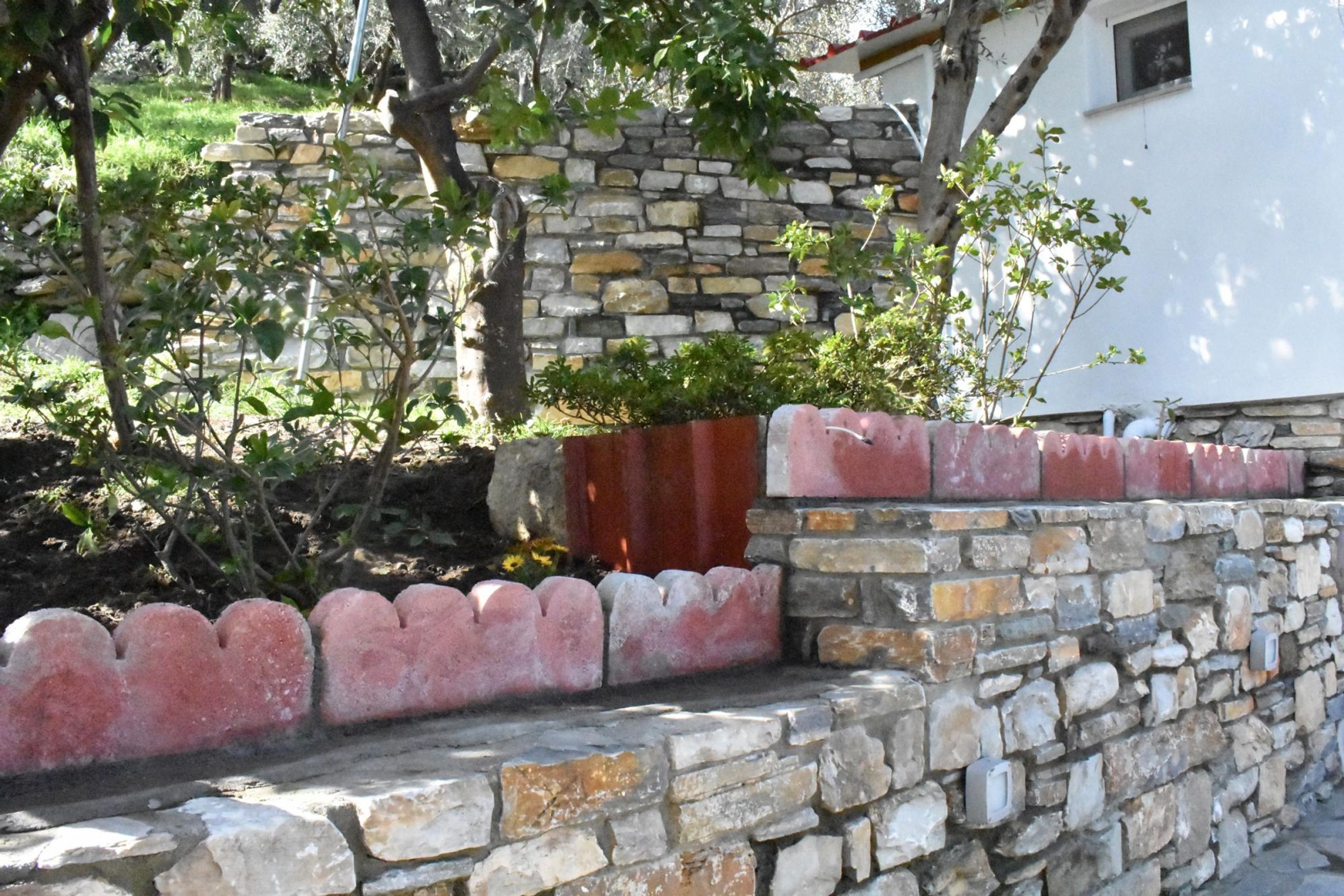 Un muro in pietra con una ringhiera rossa e una scala in pietra che conduce a un edificio.