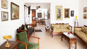 Un salon spacieux avec un canapé, des fauteuils et un coin repas à l’arrière-plan.