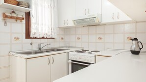 Eine Küche mit weißen Schränken, einem Herd, einer Spüle und einer Kaffeemaschine.