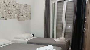 Una camera d'albergo con due letti, un armadio e una finestra con tende.