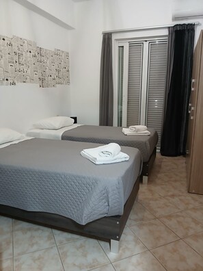 A hotel room with two beds, a wardrobe, and a window with curtains. - Chrissoula House In Agioi Apostoloi (Daratsos)