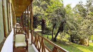 A wooden deck with chairs and a railing overlooking a lush garden. - Superior Quadruple Room Suchipakari Jungle Lodge (Napo)