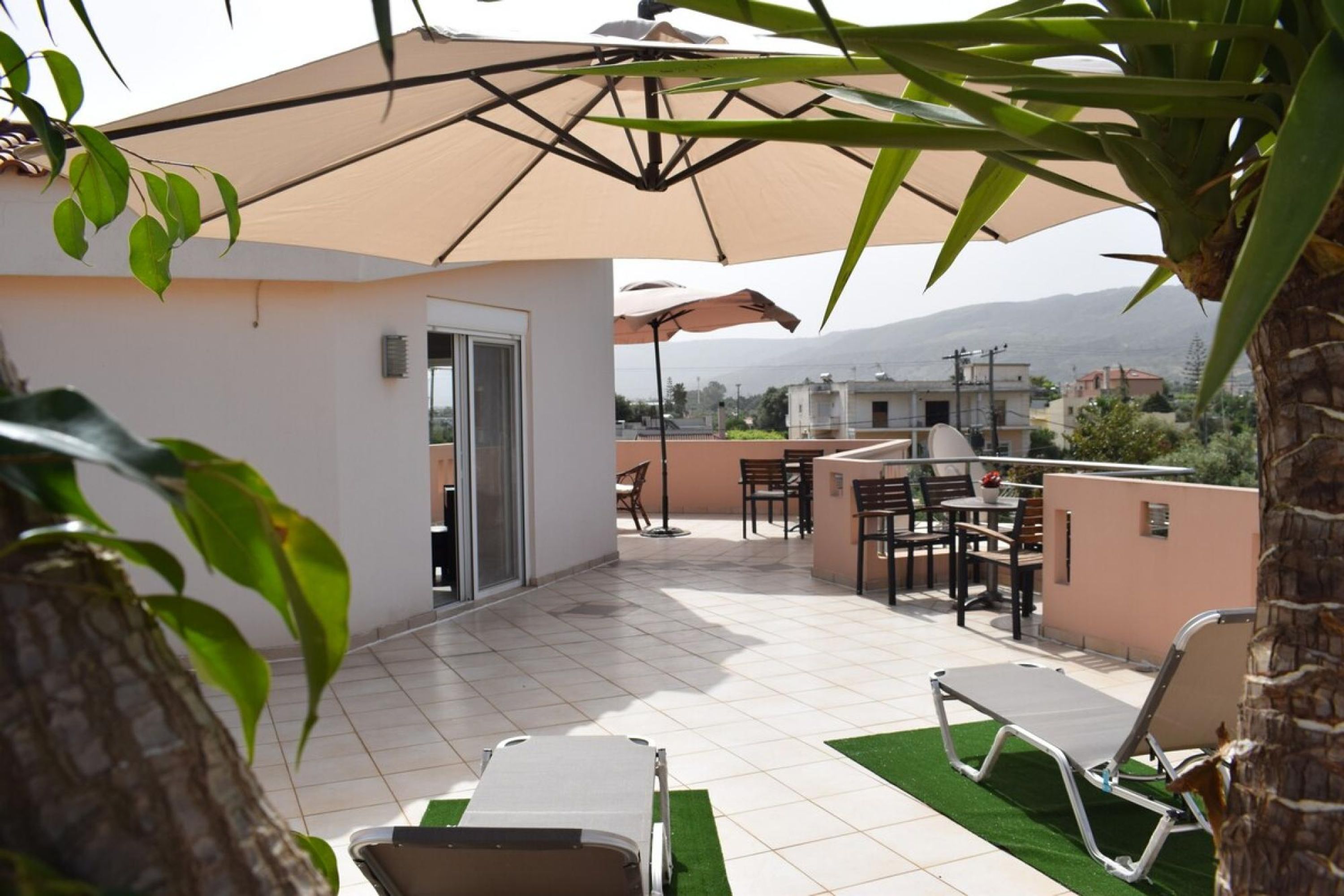 Een terras buiten met een eethoek, een pooltafel en een lounge stoel.