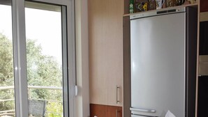Spiseområde med et bord dækket til to personer, et køleskab og udsigt til det fri.
