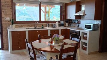 Une cuisine dotée d’un îlot central, de meubles en bois, d’une table à manger avec des chaises et d’une grande fenêtre offrant une belle vue.