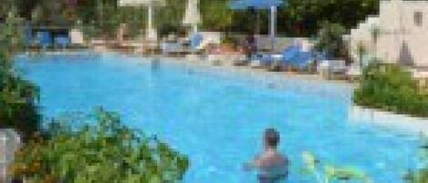Une piscine avec des chaises longues et des parasols.