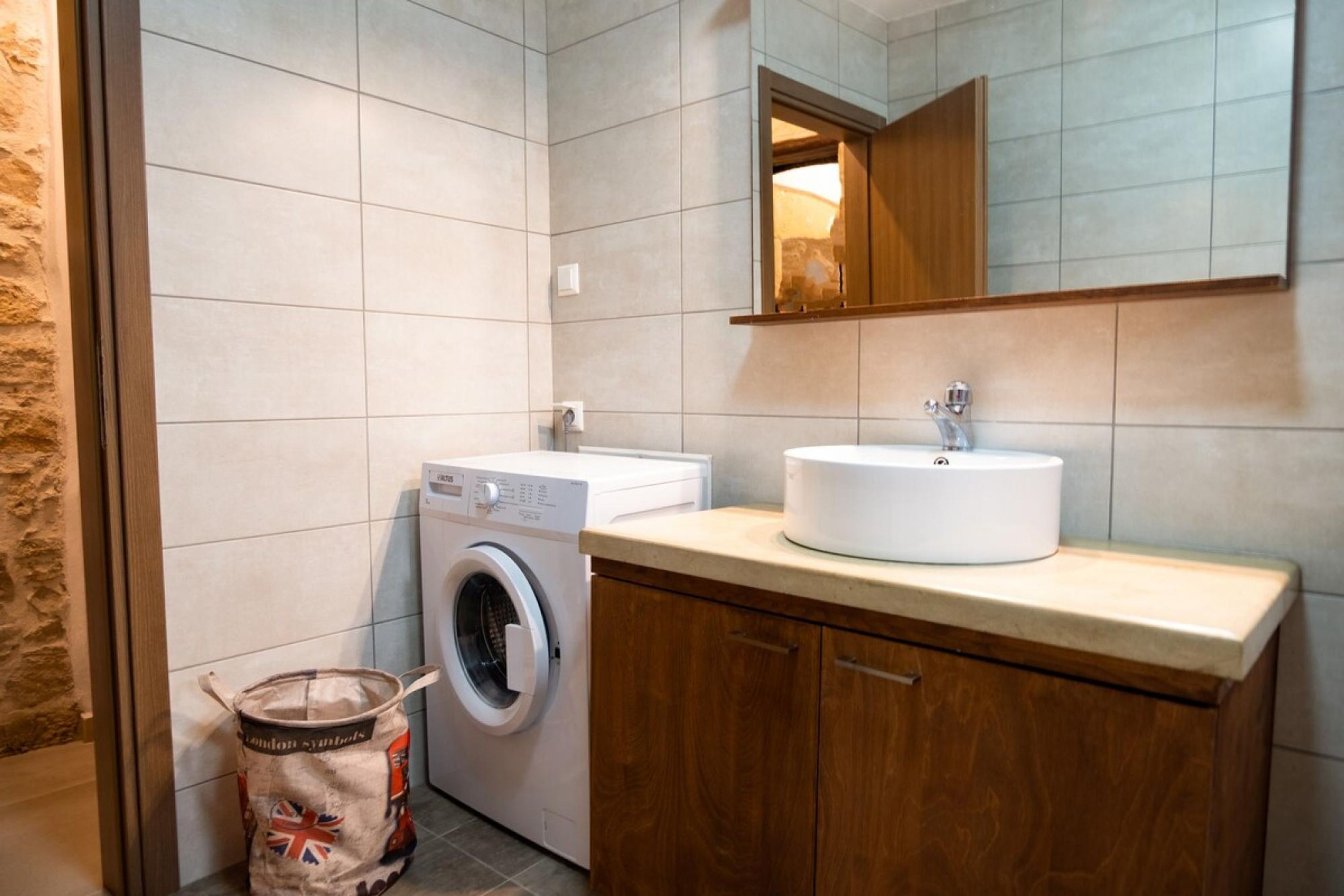 Een kleine badkamer met een wasmachine, een wastafel en een spiegel.